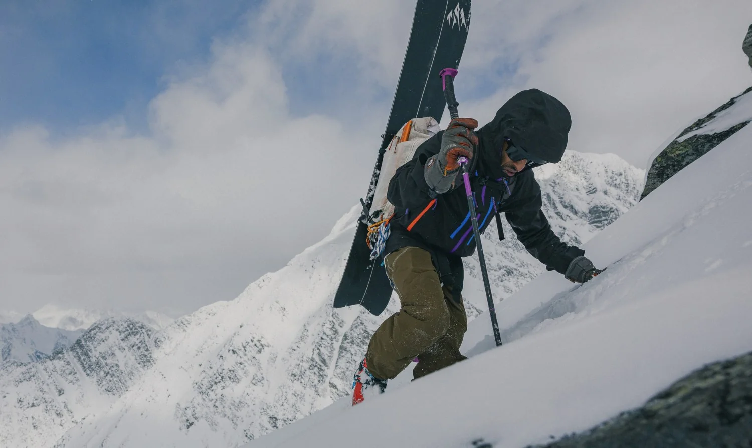 Alpinist climbing a snow slope at sunrise