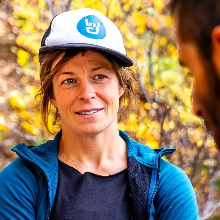 Samsara coach in a blue jacket and cap talking with an athlete outdoors in autumn