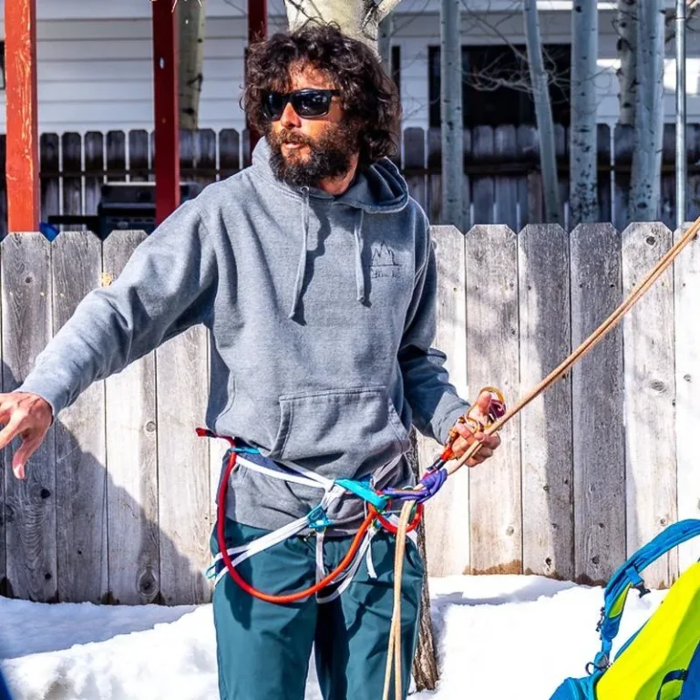 Instructor demonstrating rope and harness technique to students in the snow