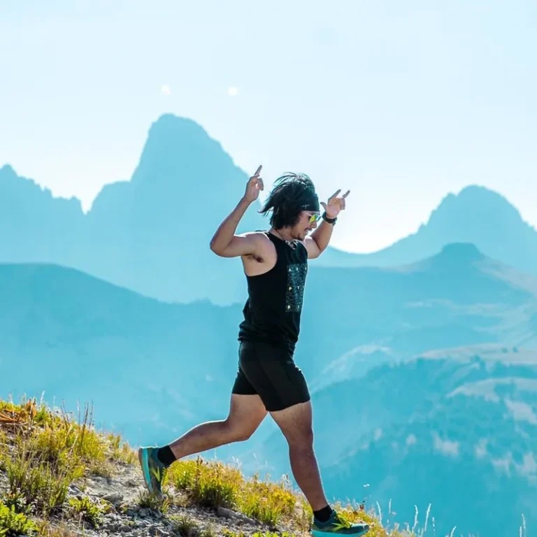 Trail runner striding up a ridgeline with the Tetons behind