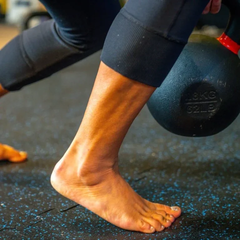 Close view of bare feet and ankles under load holding a kettlebell