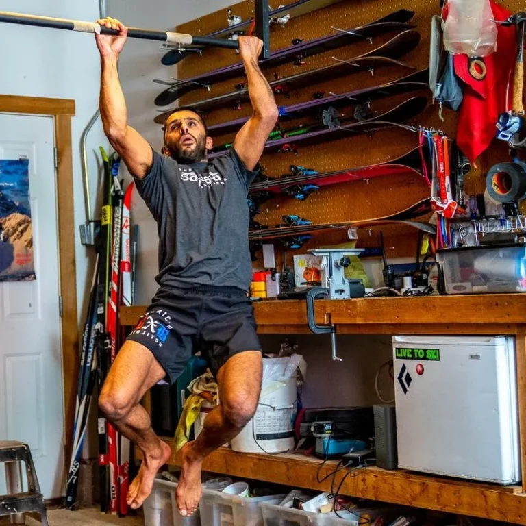 Athlete mid pull-up on a bar in a home garage gym
